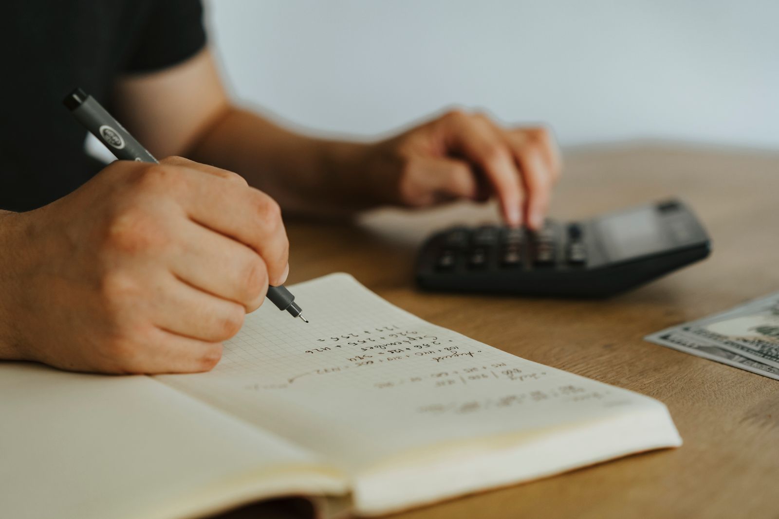 Calculator, notebook and coffee on a desk while planning a home purchase